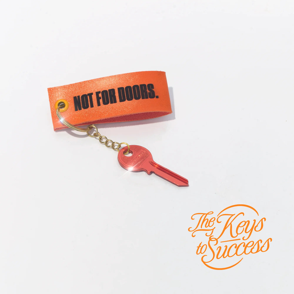 The Keys to Success keyring with a red key: orange strap printed NOT FOR DOORS.