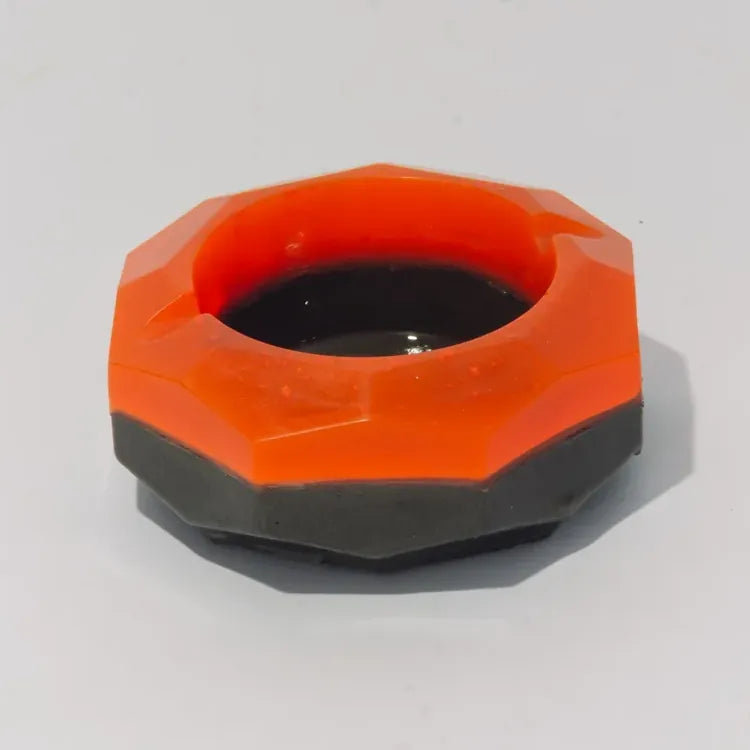 The Meteorite ashtray on a white ground: a faceted orange ring on a dark grey base